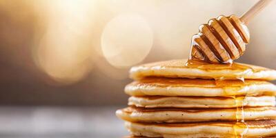 Stack of pancakes drizzled with honey, set against a warm background. photo