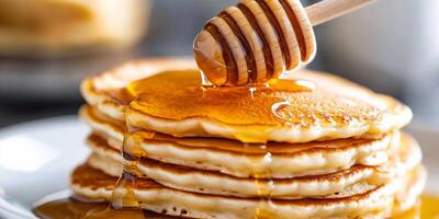 Stack of fluffy pancakes drizzled with honey, ready to be enjoyed. photo