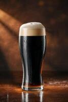 Cold glass of dark beer with foam on wooden table in warm light photo