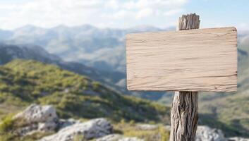 A wooden sign on a wooden post in front of a mountain range photo