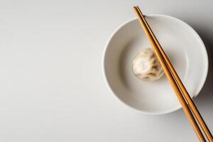 Dumplings in a bowl with chopsticks on a white background photo