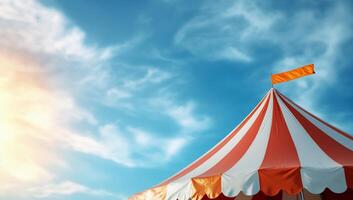 A colorful circus tent under a bright sky with a flag on top. photo