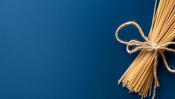 A bundle of spaghetti tied with twine on a blue background photo