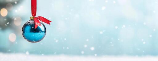 A blue Christmas ornament hangs with a snowy background. photo