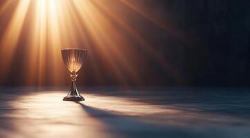 A solitary chalice illuminated by beams of light in a dark setting. photo