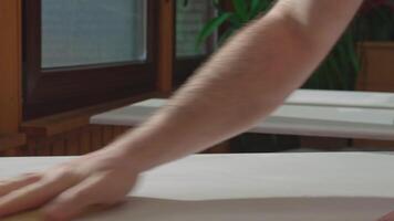 A man sanding a surface using a fleece belt. The sanded surface serves as a good base for applying paint or varnish. quality wood preparation video