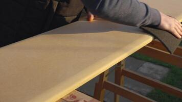 A man sanding a surface using a fleece belt. The sanded surface serves as a good base for applying paint or varnish. quality wood preparation video