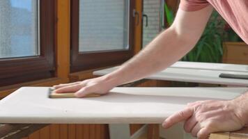 A man sanding a surface using a fleece belt. The sanded surface serves as a good base for applying paint or varnish. quality wood preparation video