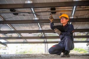 A solar panel installer points his finger at a faulty power line and notes it on a clipboard. photo