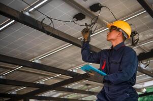 A solar panel engineer monitors the electrical system of his panels using a tablet he holds in his hand photo