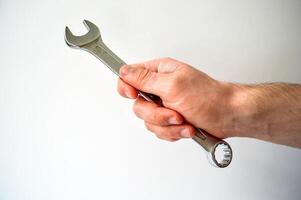 Man's hand holding wrench isolated on white background photo