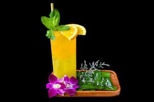 Orange juice with slice of orange, with flowers isolated on black background photo