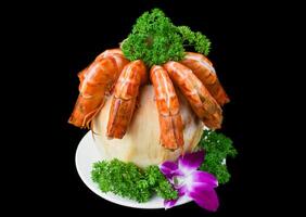 Orange shrimps inside of coconut with sauce isolated on black background side view photo