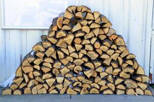stacked pile of firewood with snow on a white wall background photo