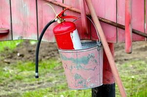 Fire extinguisher in a bucket hanging on a red board photo