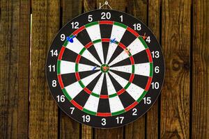 darts hanging on a wooden wall with a dart stuck in the center photo