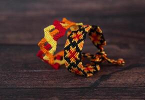 Tied friendship bracelets with bright colorful patterns handmade of thread isolated on white background photo