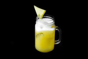 Glass of fresh pineapple juice with ice isolated on black background photo