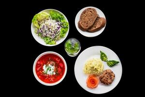 set with borscht, mashed potato, black bread, salad on black background top view photo
