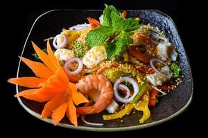 Thai salad made of shrimps and squid and onion isolated on black background side view photo