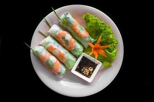 Traditional vietnamese spring rolls with shrimps, rice paper on black background top view photo