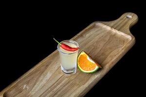 Alcohol shot made of orange juice and chili on wooden board with with copy space photo