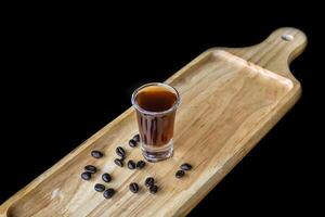 Alcohol shot made of coffee on wooden board with coffee beans with copy space photo