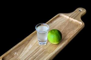 Alcohol shot made of lime juice on wooden board with with copy space photo