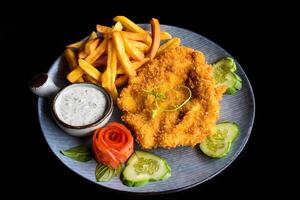 Chicken chop steak with vegetables on blue plate isolated on black background side view photo