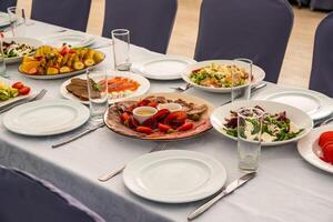 festive table set with Caesar salads, beets, fruit plate without people photo