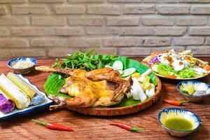 Grilled chicken in vietnamese style with colorful rice in bamboo, and boiled eggs on wooden table photo