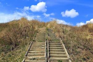 Abandoned stairs overgrown, leading to the blue sky with clouds. Concept of stairway to Heaven or thorny path to the beautiful. photo