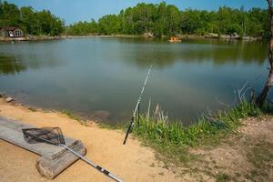 fishing rod and net for fishing against the backdrop of a pond and forest. summer activities photo