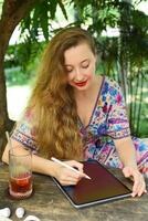 Beautiful blonde woman artist and illustrator draw sitting by the table with electronical tablet and stylus photo