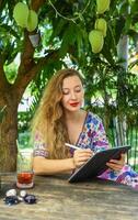 Beautiful blonde woman artist and illustrator draw, sitting by the table with electronical tablet and stylus photo