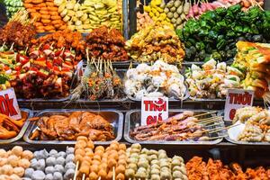 Many snacks and seafood in vietnamese night market with signs with vietnamese text time, price translation photo