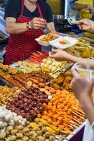 Vietnamese woman serving chicken paws in plastic box with chili in vietnamese night market photo