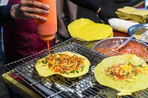 Grilled vietnamese pancake with eggs, sausage and sauces in vietnamese night market in food festival photo