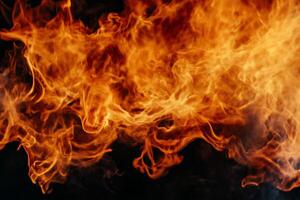 Fiery flames against a dark backdrop. Flames dance and swirl in a chaotic pattern of orange and yellow, creating an intense visual. Smoke plumes gently intermingle with the heat photo