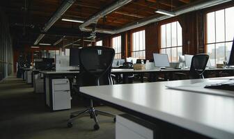 Empty modern office space with rows of desks, computers, and chairs. Large windows offer city views. Industrial style photo