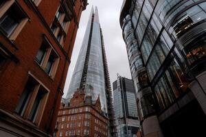 London skyscraper amidst historic buildings. View from street level, looking up at modern high-rise photo