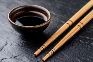Small bowl of dark soy sauce with chopsticks on a dark stone surface photo