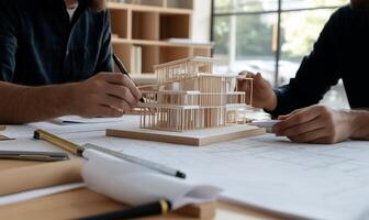 Architects collaborating on a building model. Detailed architectural plans and blueprints surround the model photo