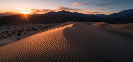 Sunset over desert dunes, mountains in background photo