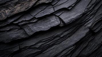 Dark, layered stone texture with rough, angular surfaces photo