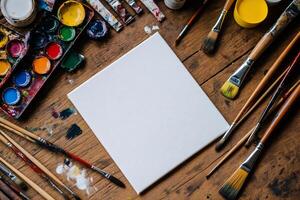 Blank canvas surrounded by paints and brushes photo