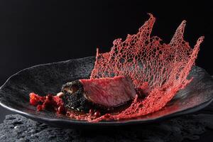 Slow-braised short rib with kombu and mirin reduction garnished with red algae lace tuile for a modern culinary experience photo