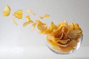 Glass bowl filled with golden potato chips, floating mid air with freshness photo