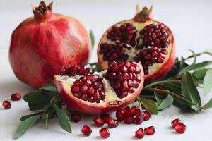 Halved pomegranate with ruby red seeds and golden arils, set against a white background photo