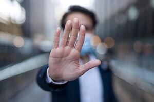 Partially obscured individual extends hand in a stop gesture, symbolizing resistance photo